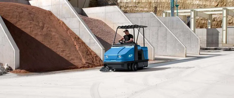 Sweeper machine clearing an outdoor hardstand yard