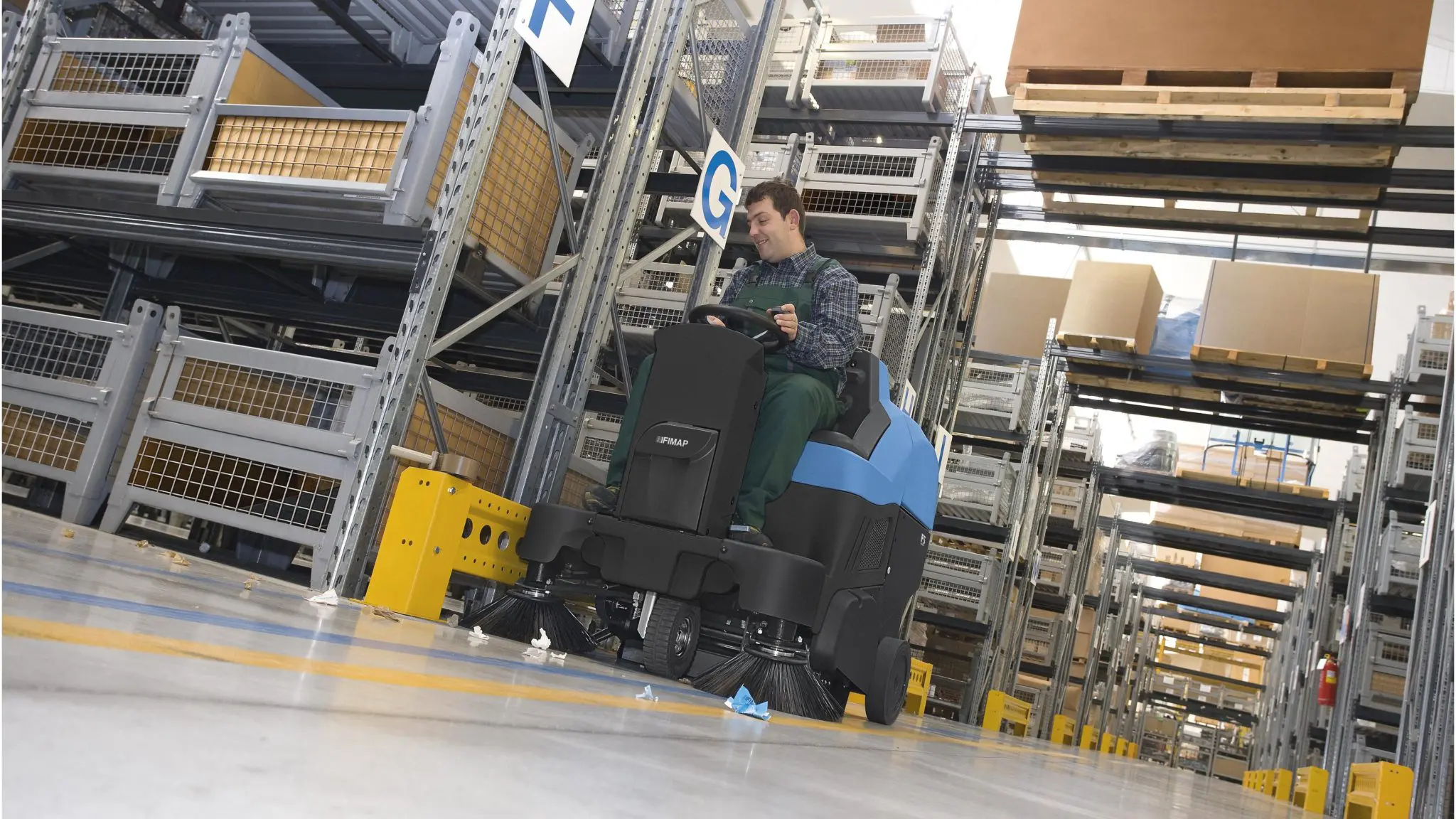 Walk-behind sweeper working between warehouse racking